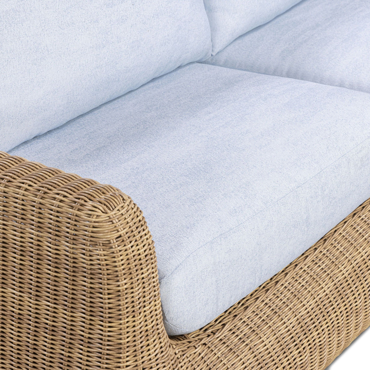 Close-up of outdoor sofa seating with light blue cushion and woven wicker