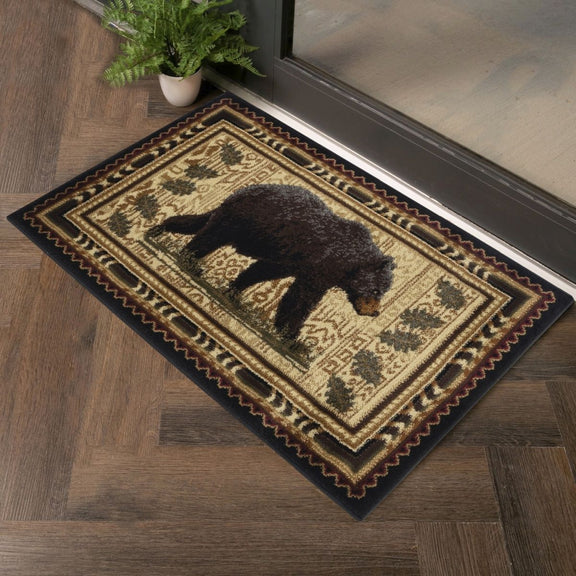 Rectangular rug with black bear silhouette, tan cream field, and multicolor tribal border