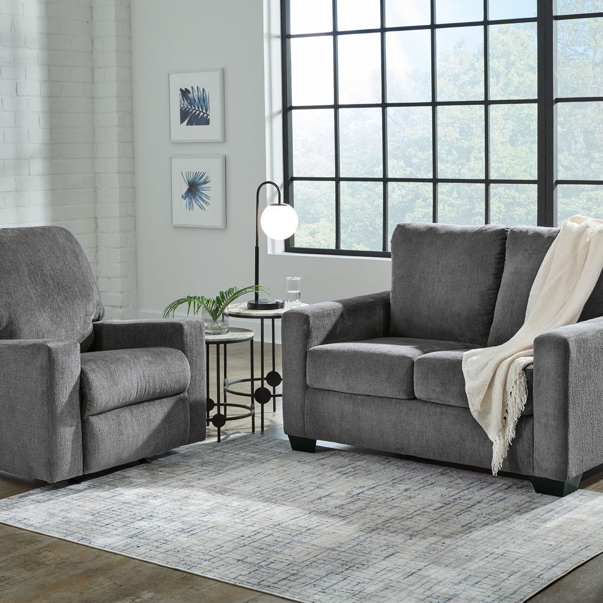 Dark gray fabric living room sofa with matching armchair, cushioned seats and blanket
