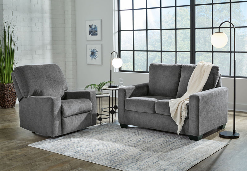 Dark gray fabric living room sofa with matching armchair, cushioned seats and blanket