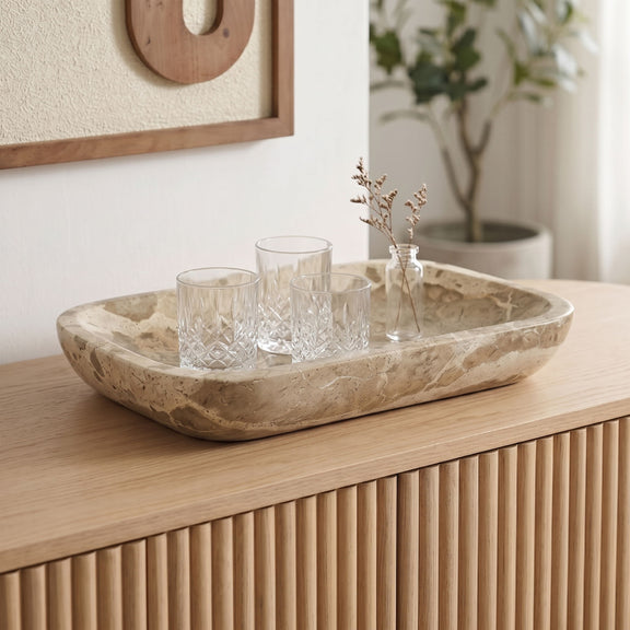 Brown marble serving tray with light veining and shallow oval shape on a wooden surface