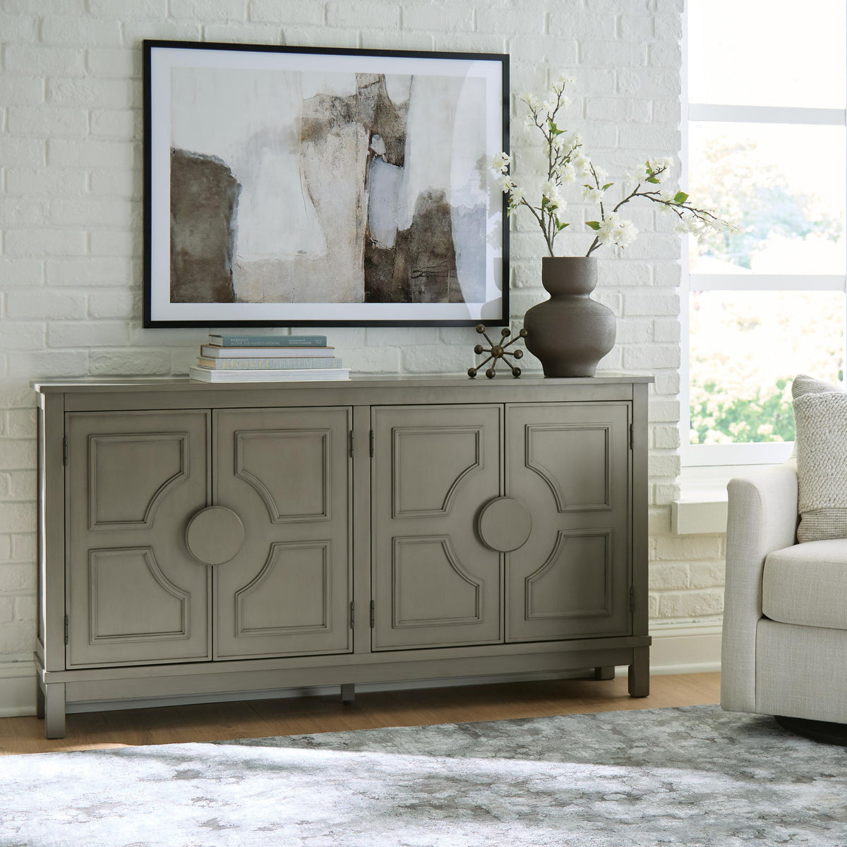 Warm gray accent cabinet with four raised panel doors and round center knobs