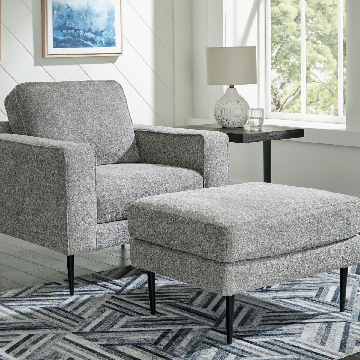 Charcoal upholstered chair with matching ottoman, black tapered legs and square arms