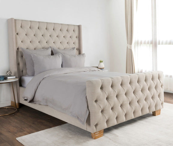 Charcoal pillow sham on bed with tufted headboard and light bedding