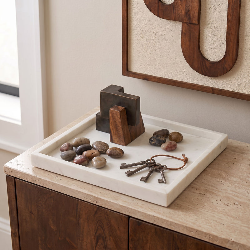 Rectangular marble tray with gray-white base holding stones and metal keys.