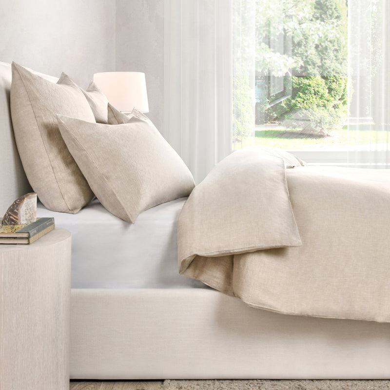 Natural beige linen cashmere duvet draped on a sofa with coordinating pillows