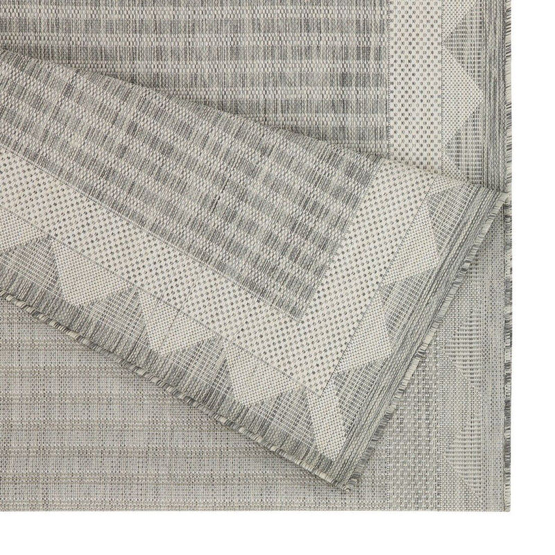 Gray area rug with geometric border and fringed edge