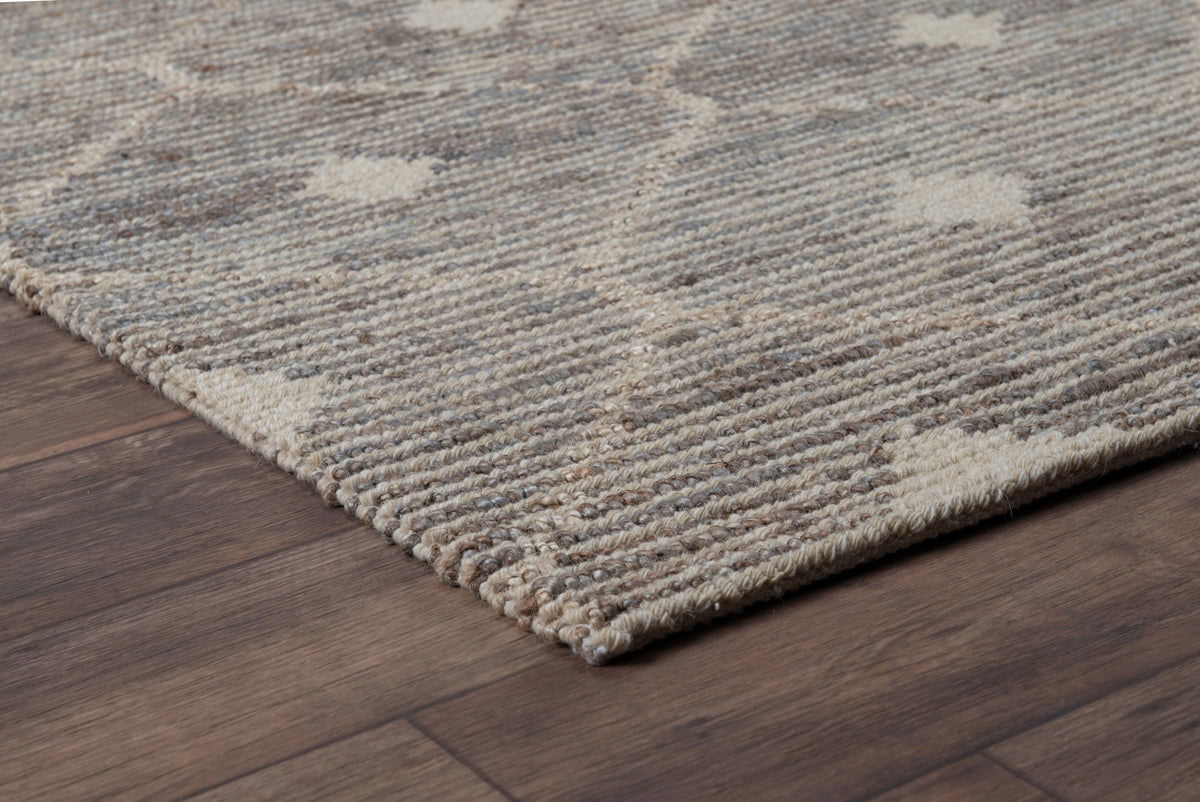 Stone and cream rug corner with braided texture and flatwoven pile.