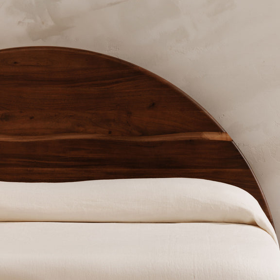 Close-up of brown arched headboard with curved wooden paneling