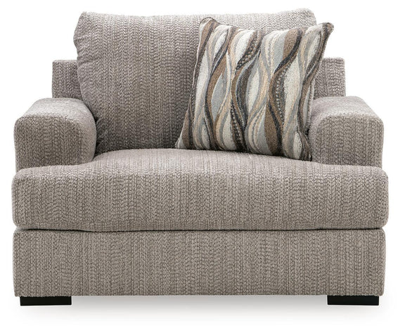 Gray chair and a half with patterned throw pillow, rolled back, and thick arms