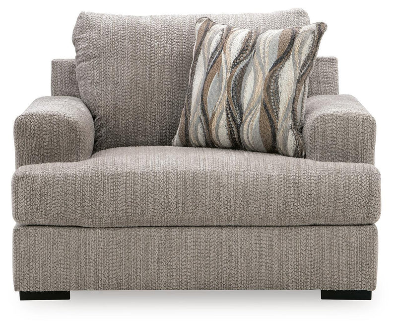 Gray chair and a half with patterned throw pillow, rolled back, and thick arms
