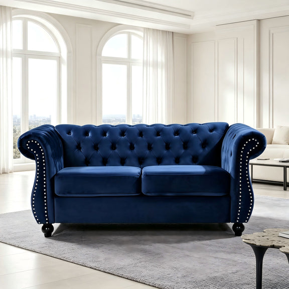 Blue tufted button loveseat with rolled arms and studded nailhead trim in a living room.