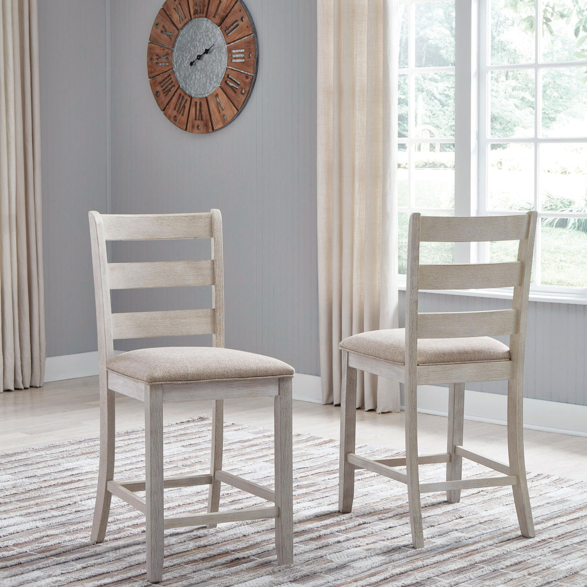 Two white upholstered barstools with ladder backs and light beige seat cushions