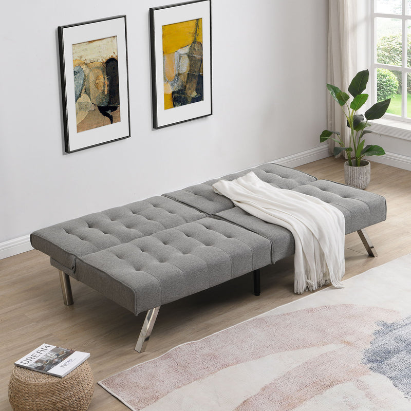Gray futon sofa bed opened flat as a bed with tufted mattress
