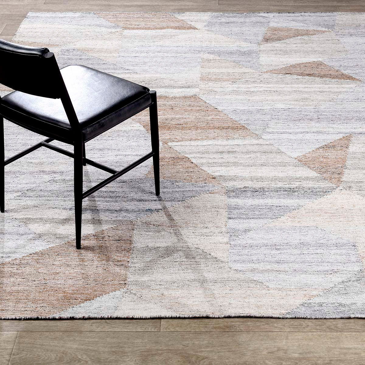 Abstract geometric rug corner with distressed blocks in off-white, pale blue, and tan