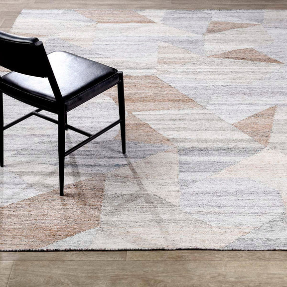 Abstract geometric rug corner with distressed blocks in off-white, pale blue, and tan