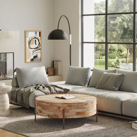 Natural wood drum coffee table with black legs in a living room