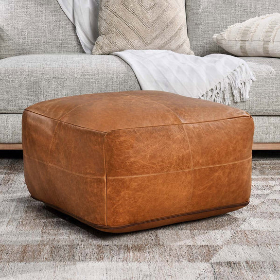 Chestnut leather pouf ottoman with top and side panel stitching.