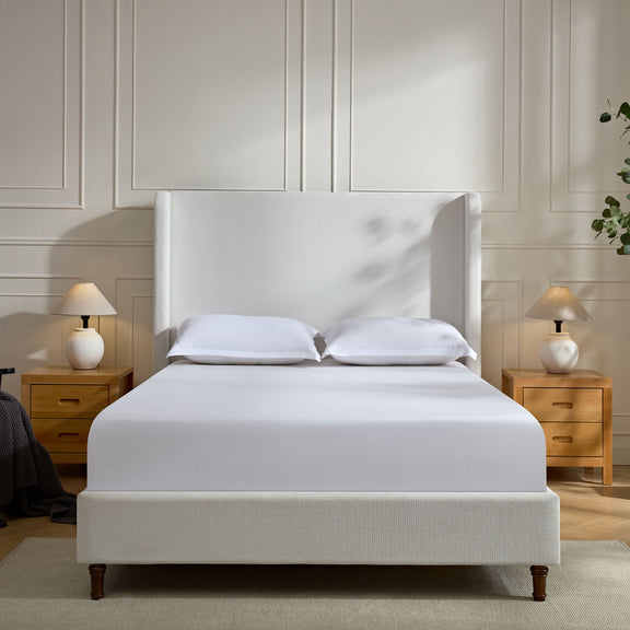 White upholstered bed with tall headboard and two pillows, centered view