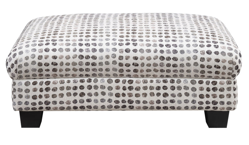 Tufted ottoman top with dark ink-dot pattern on light fabric and dark wooden legs