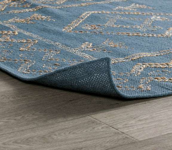 Blue rug corner close-up with stitched geometric border in gold on low pile