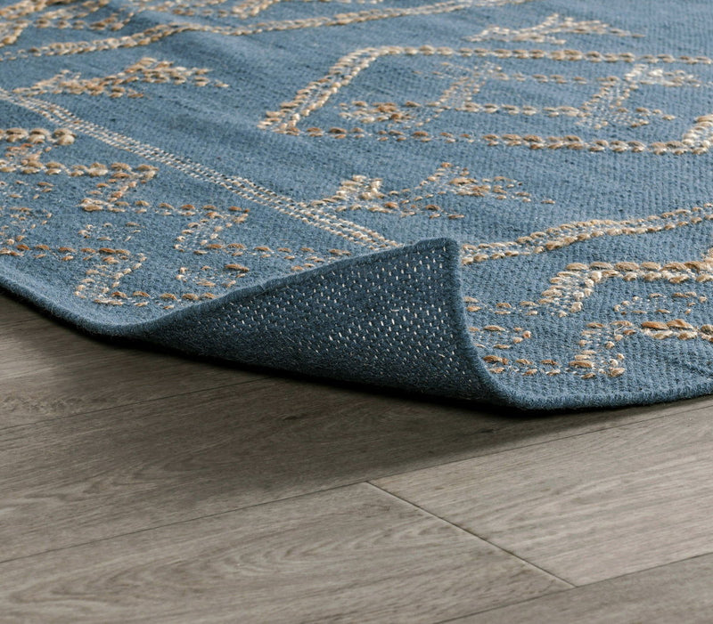 Blue rug corner close-up with stitched geometric border in gold on low pile