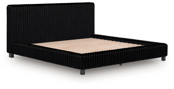 Black upholstered bed frame with vertical ribbed headboard and beige mattress