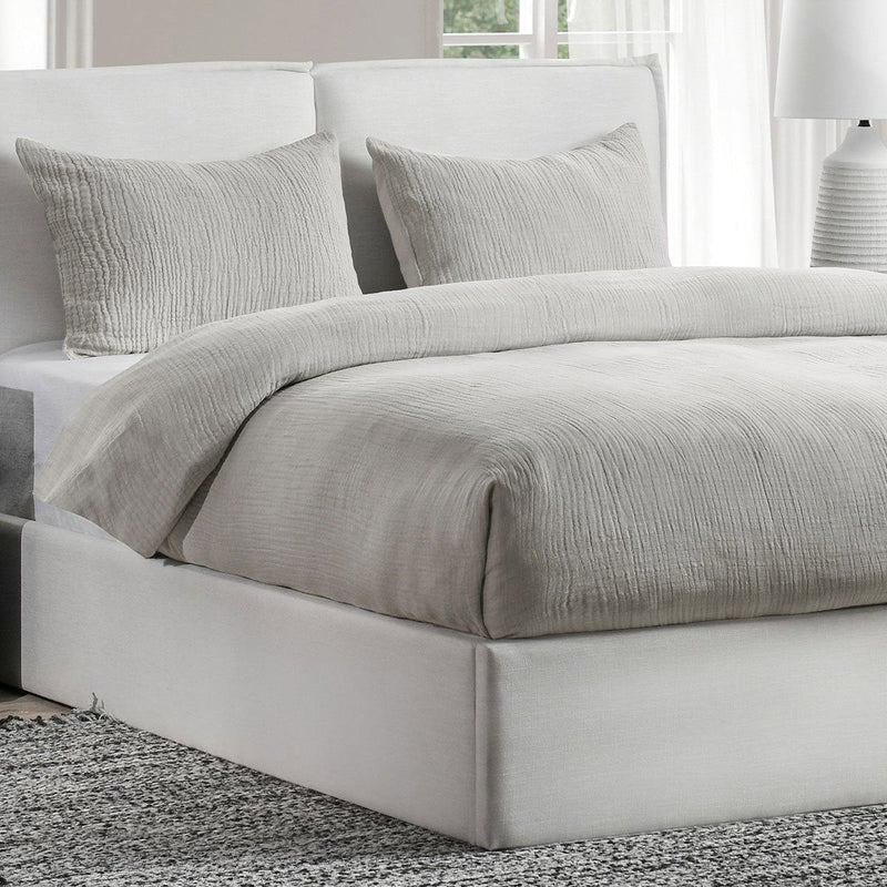 Light gray textured sham pillow on bed with matching pillows
