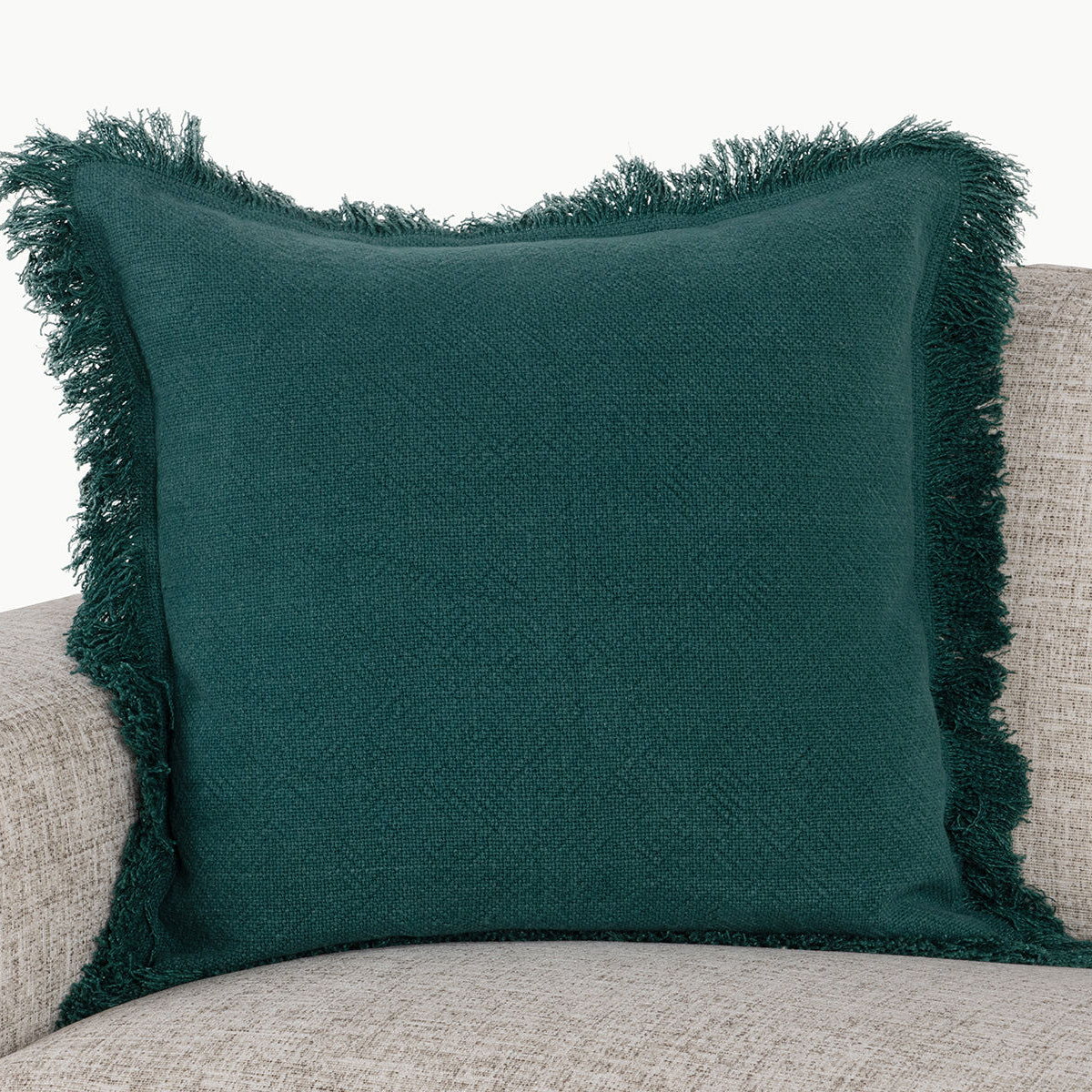 Deep green square accent pillow with textured fabric and fringed border