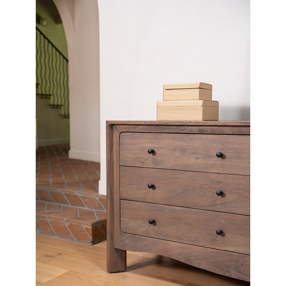 Dark brown dresser with three front drawers and black knobs, warm wood top
