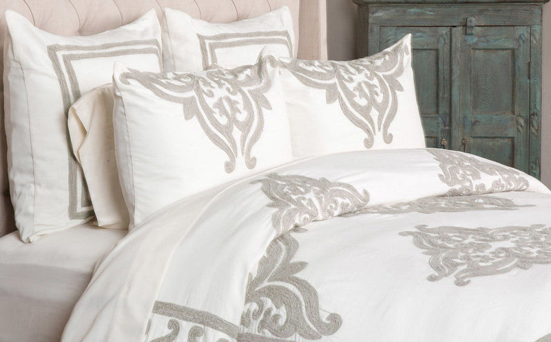 Ivory duvet featuring gray damask design with coordinating decorative pillows on bed