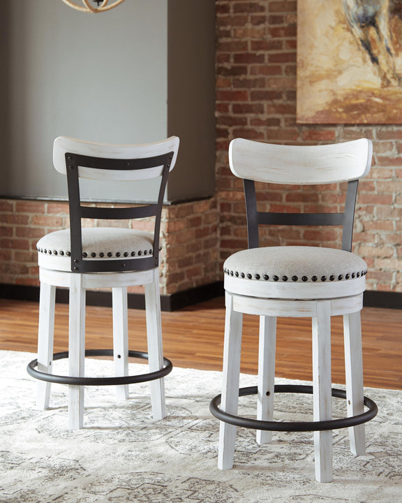 Two white swivel bar stools with full backs, studded upholstered seats, and base rings