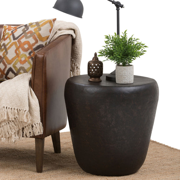 Handcrafted metal side table in dark brown, rounded drum top with tapered base and hammered texture.