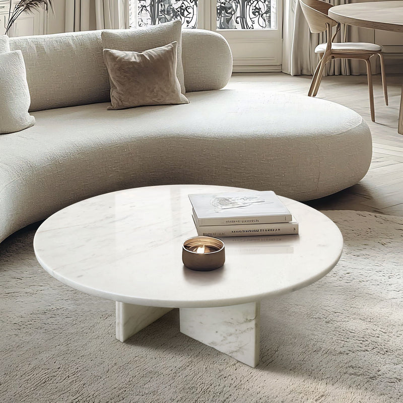 Round white marble coffee table with sculpted stone base and subtle gray veining