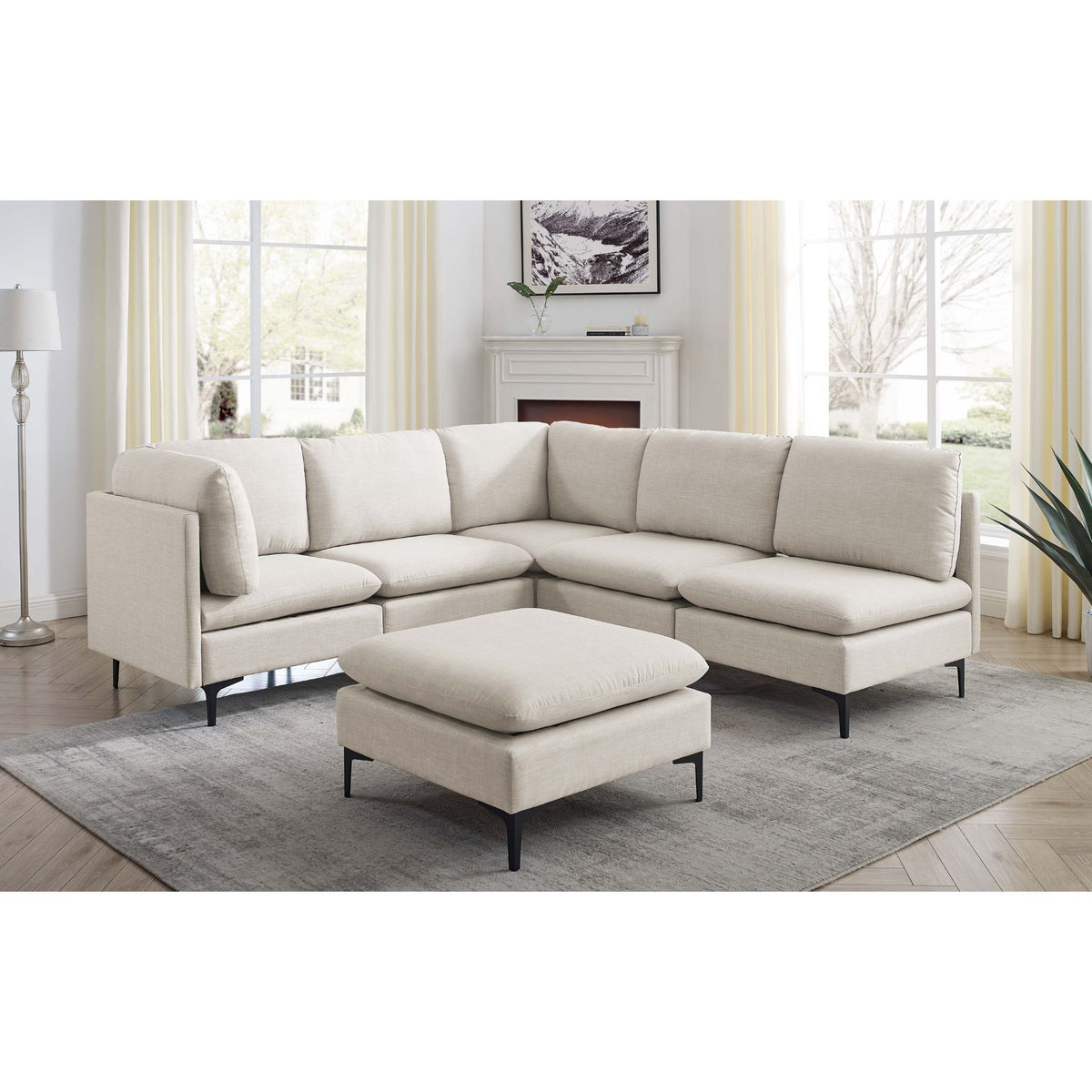 Beige L-shaped sectional with ottoman and tall black legs, rounded arms