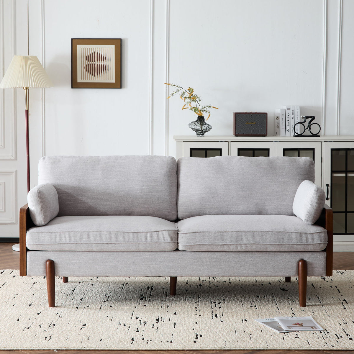 Light gray sofa with dark wood arms and legs, styled with decor in a room