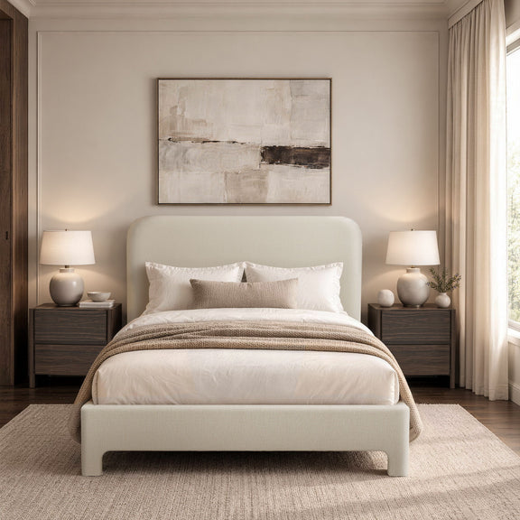 Beige upholstered bed with rounded headboard, white bedding, and striped throw blanket