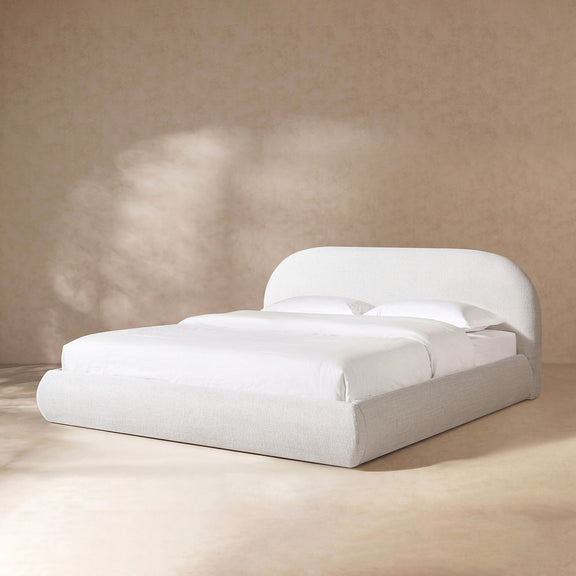 Upholstered platform bed in white fabric with padded headboard and slat support