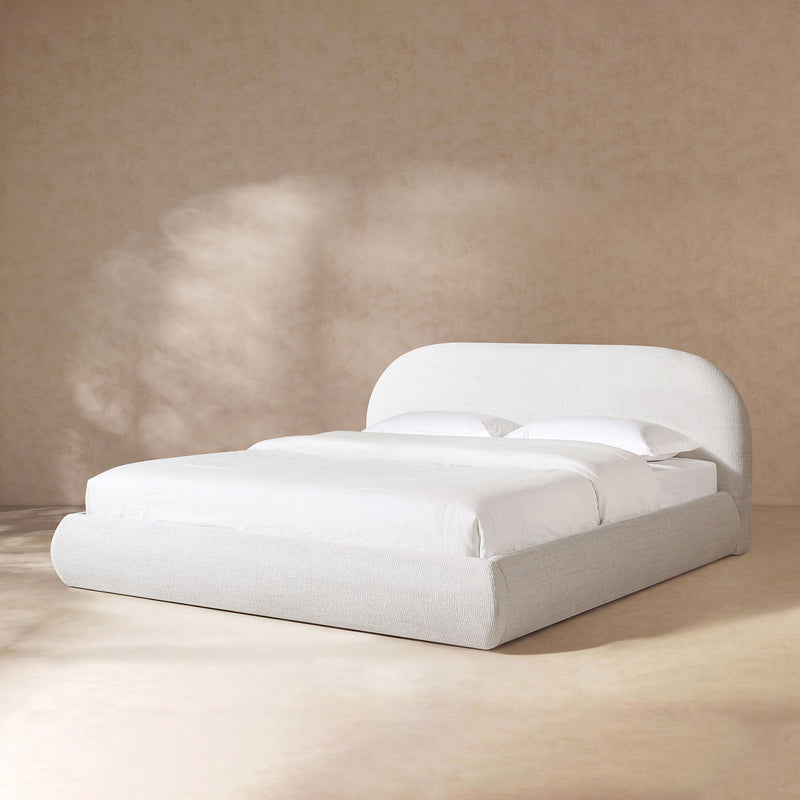 Upholstered platform bed in white fabric with padded headboard and slat support