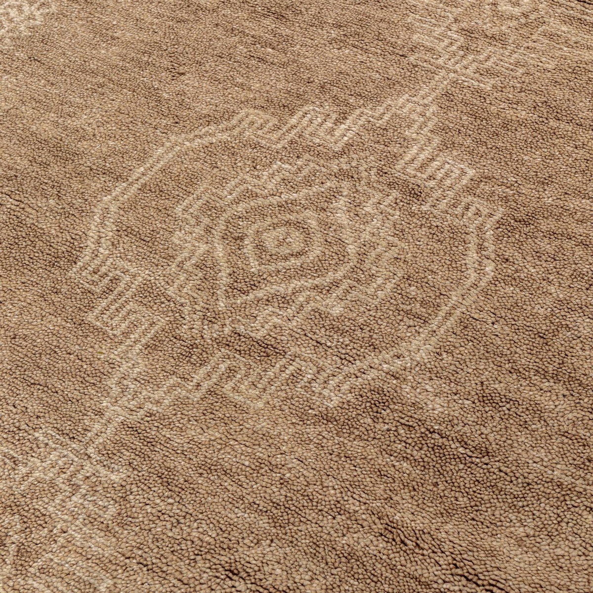 Desert brown hand-knotted rug close-up with geometric medallion motif.
