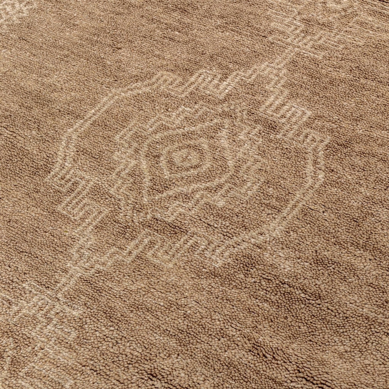 Desert brown hand-knotted rug close-up with geometric medallion motif.