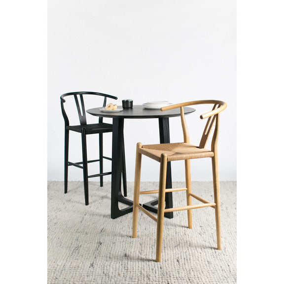 Round black ash counter table with sculpted pedestal legs and compact top