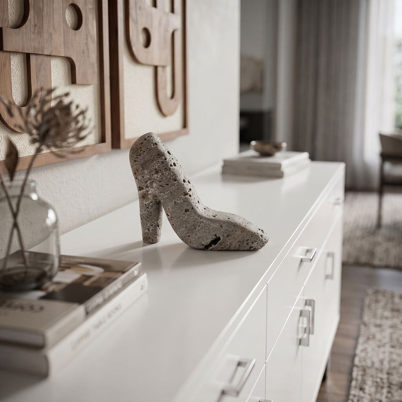 Gray high-heel shoe tabletop sculpture on a white console, speckled stone