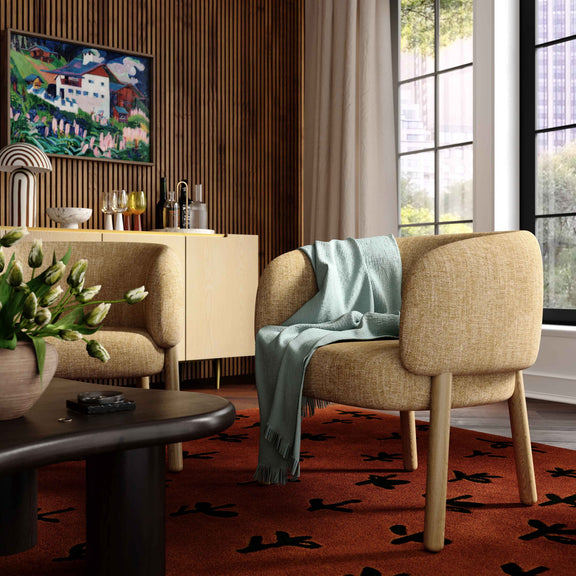 Beige upholstered accent chair with curved back and armrests, wooden legs