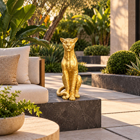 Gold leopard statue seated upright beside an outdoor sofa, with a curled tail and spotted texture