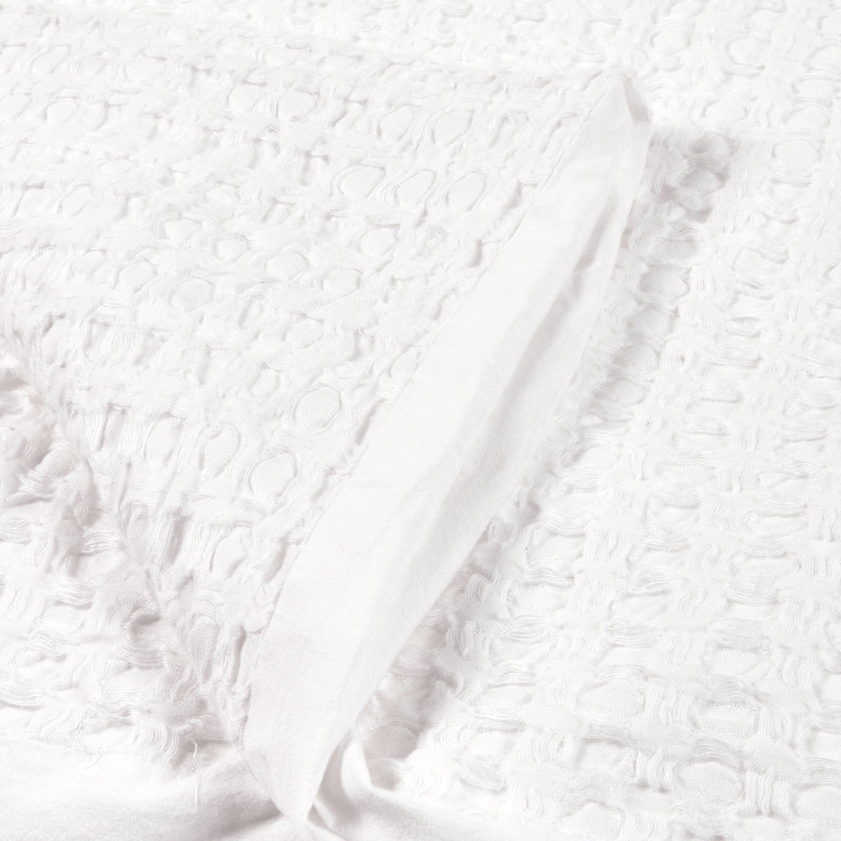 Close-up of white quilt fabric with embossed textured surface.
