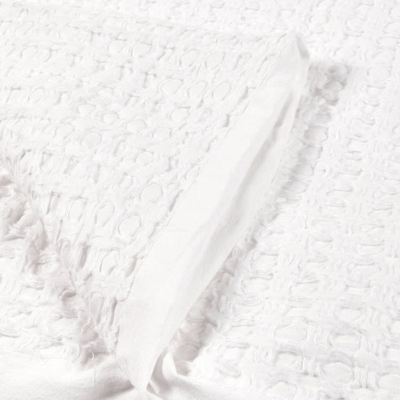Close-up of white quilt fabric with embossed textured surface.