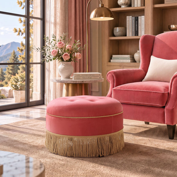 Pink round upholstered ottoman with tufted top and gold fringe tassels