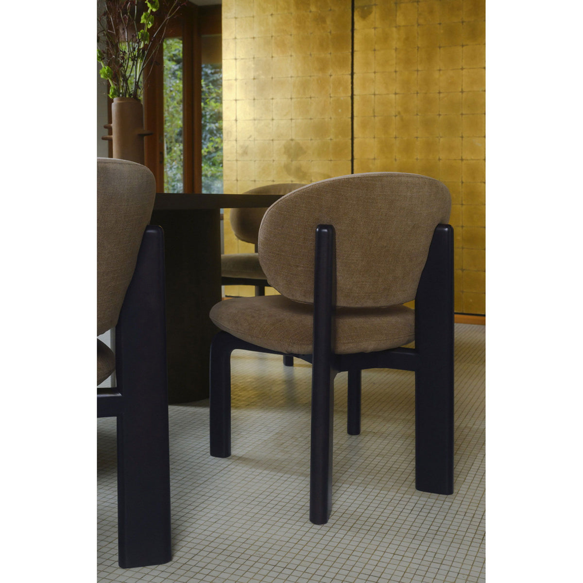 Tan upholstered dining chair with curved back and dark brown legs, three-quarter angle