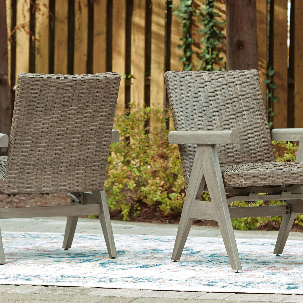 Two beige woven rocking arm chairs with light wood arms